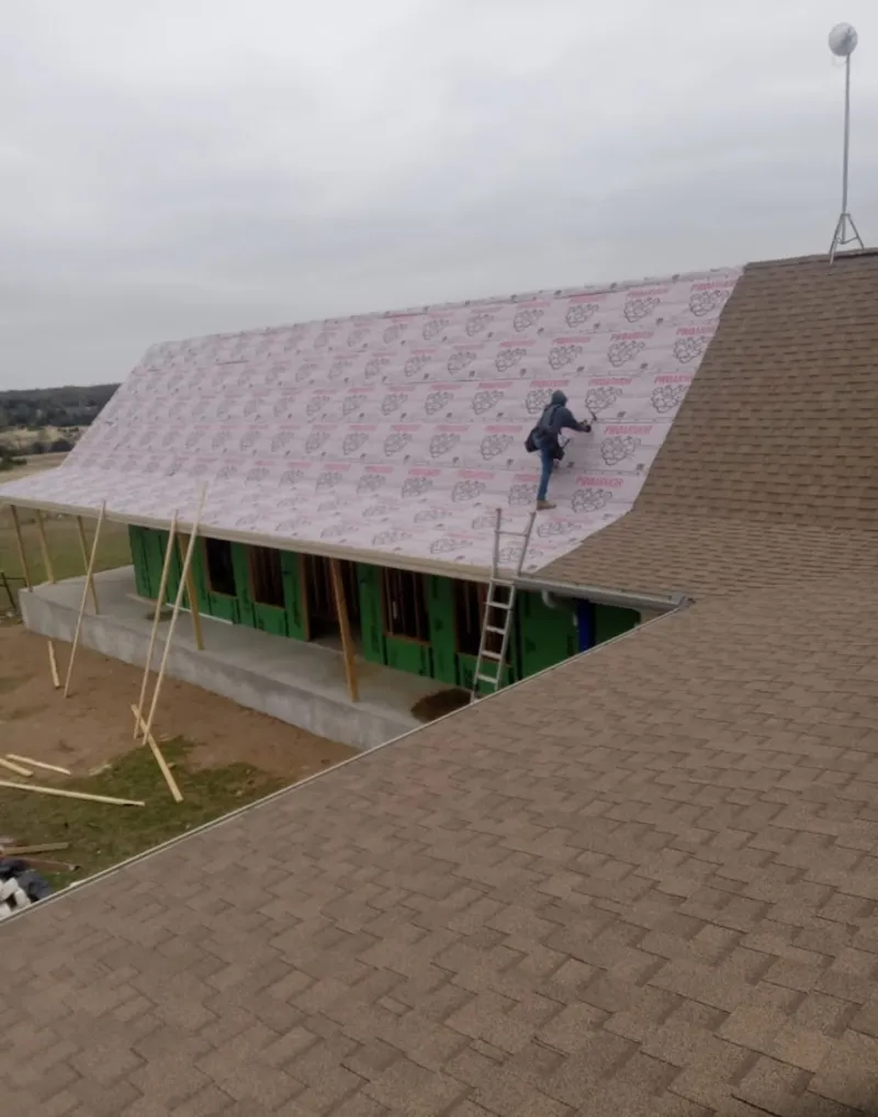 Worker preparing underlayment for a metal roof installation in Severn
